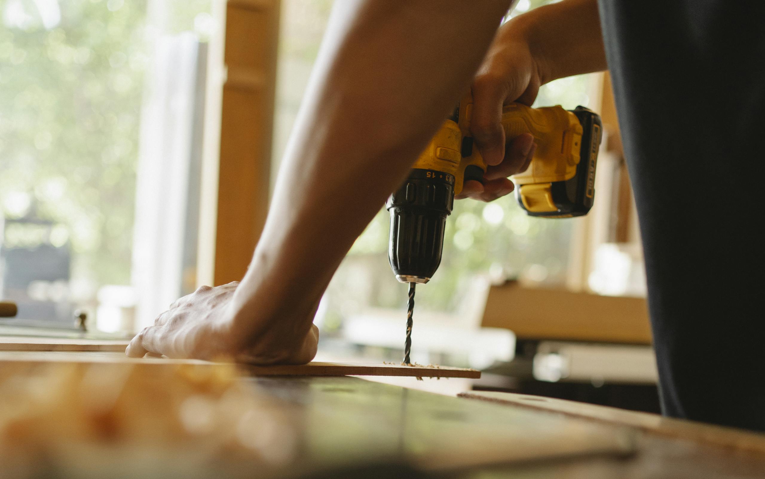 Man drilling wooden plank on desk