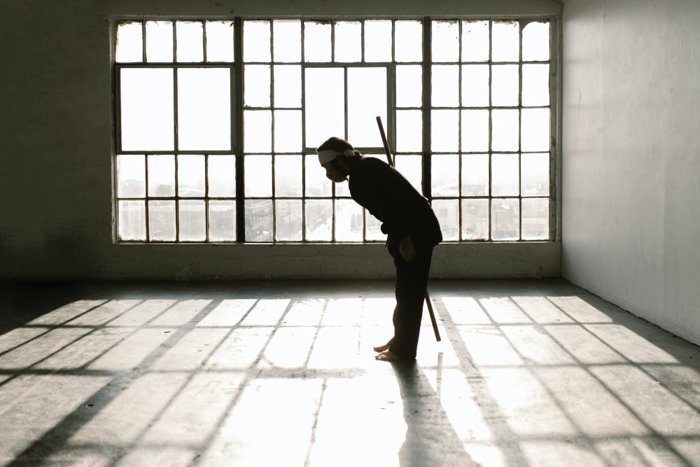 Martial artist with bo staff bowing in empty room